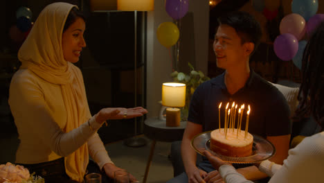 Multi-Cultural-Group-Celebrating-Friends-Birthday-At-Home-With-Cake-And-Candles-At-Party-1
